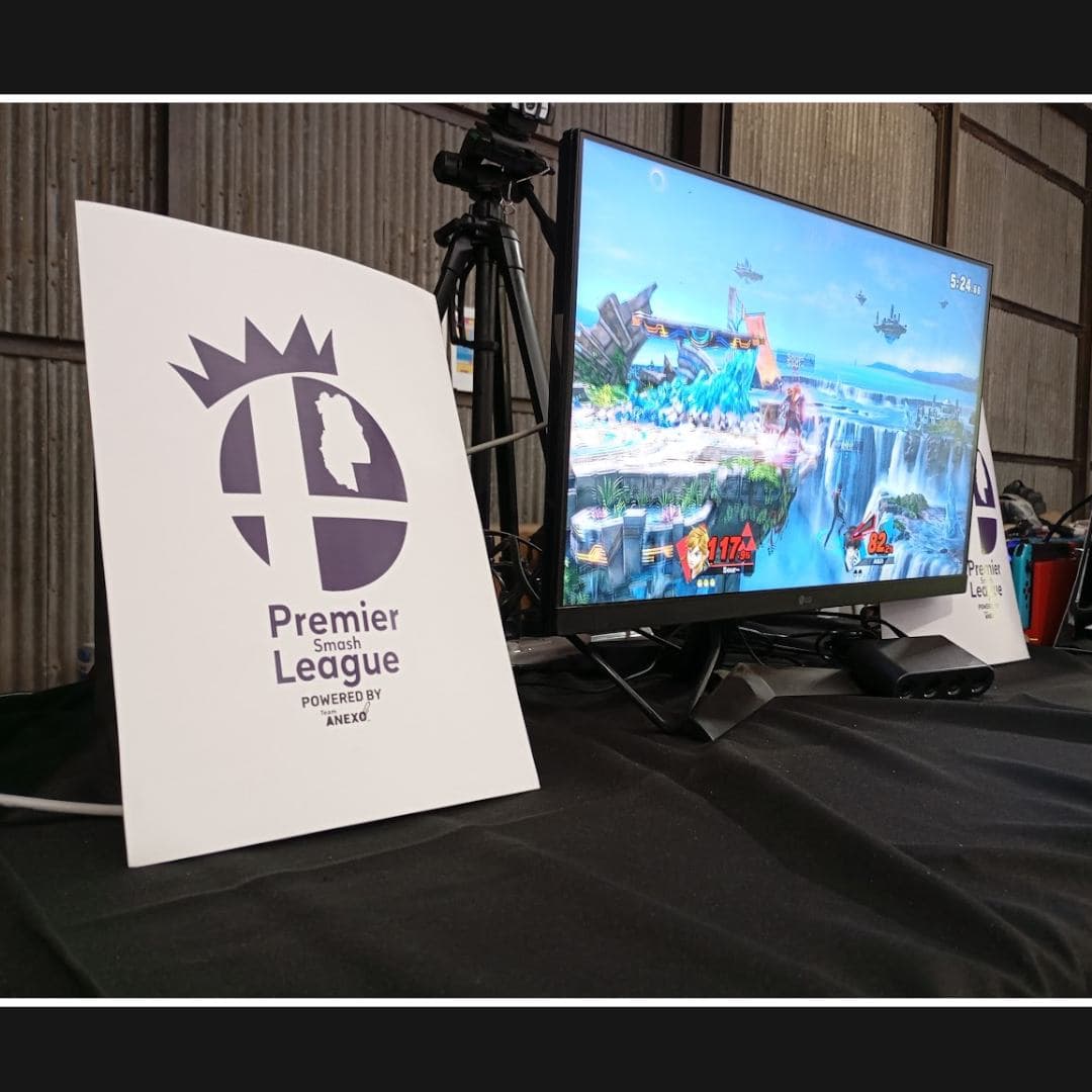 Cartel de la Premier Smash League junto a un monitor con Smash Bros